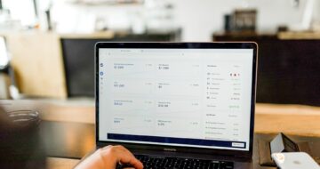 Someone is on their laptop, the screen displays different metrics and graphs.