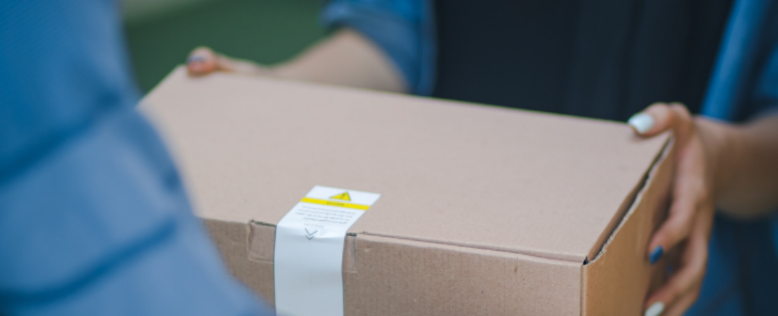 One person is handing a brown cardboard package to another persion